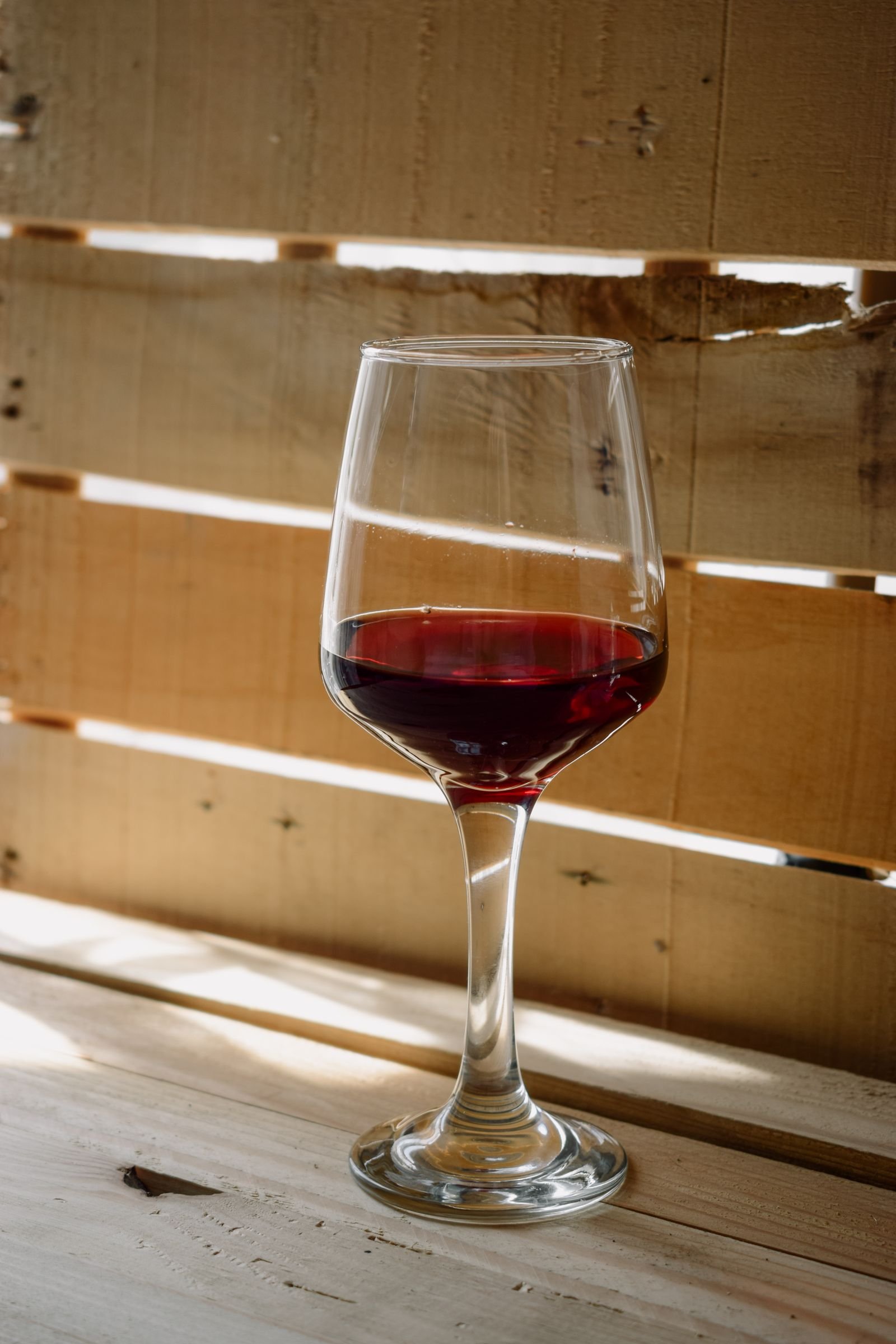 Copa de vino tinto sobre una mesa de madera rústica
